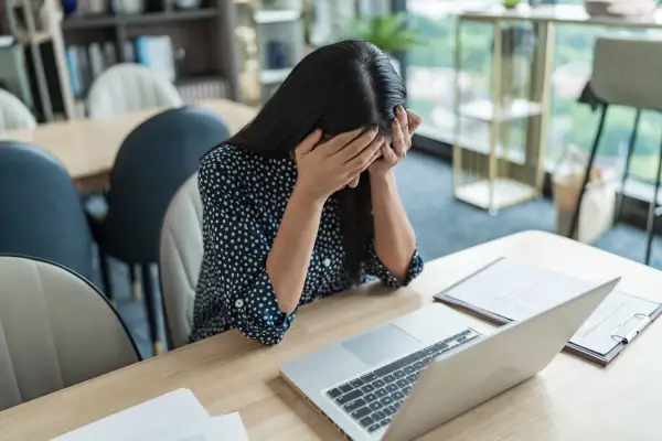 A stressed woman with her hands on her head. Stress management can help cure PCOD naturally.